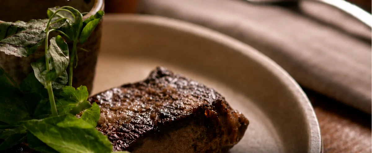 A perfectly cooked steak on a ceramic plate with fresh herbs